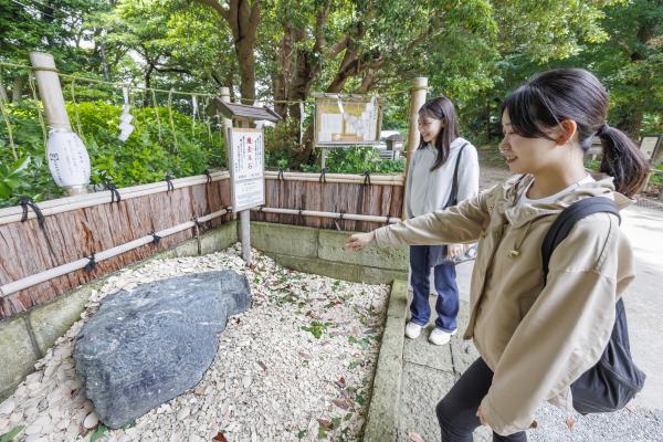 魔去る石を指さす女性の写真